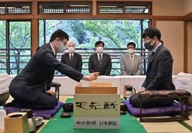 天元戦第１局で初手を打つ一力遼碁聖（左）と井山裕太天元＝８日午前、名古屋市、賀城園