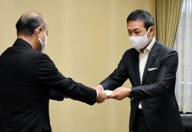 黒川優副市長（左）に申し入れ書を手渡す石堂大輔副議長＝９日午後３時半ごろ、姫路市役所
