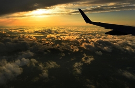 機内から見えた夕焼けの空。オレンジ色に染まる雲が海原のように眼下に広がっていた