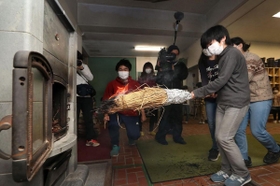 自分たちでおこした火をストーブに移す児童ら＝２３日午前、神戸市立六甲山小学校