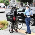 食事宅配サービス配達員に、交通ルールを守るよう呼び掛ける警察官＝神戸市中央区