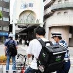 食事宅配サービス配達員に、交通ルールを守るよう呼び掛ける警察官＝神戸市中央区