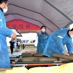 新型コロナ対策で人形を負傷者に見立て、自身も防護服を着用して訓練に参加する医療関係者ら＝１９日午後、神戸空港（撮影・中西幸大）