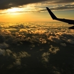 機内から見えた夕焼けの空。オレンジ色に染まる雲が海原のように眼下に広がっていた