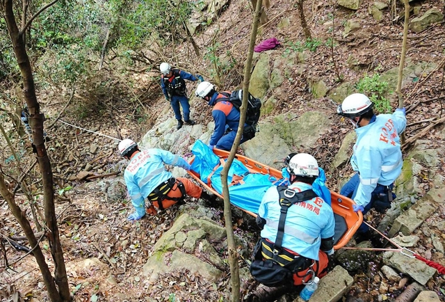 六甲山系の険しい斜面で、傷病者を搬送する神戸市消防局の救急隊員ら。今年は出動が増えている＝２０１９年４月、神戸市中央区（同消防局提供）