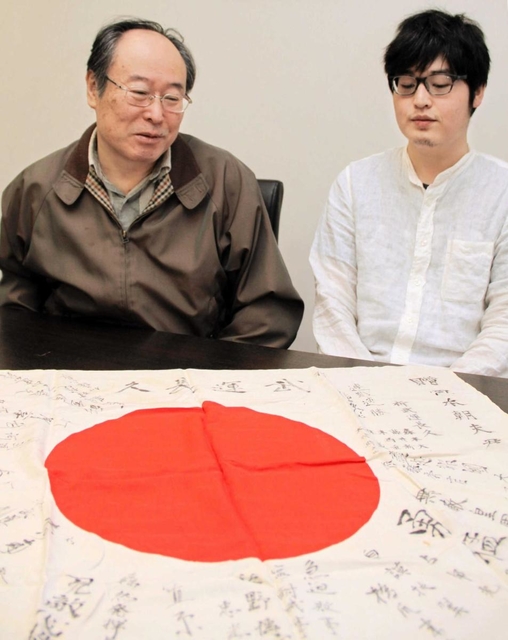 戦後７５年の節目に、姫路へ帰ってきた日章旗を見つめる岡本明さん（左）と四男崇宏さん＝姫路市本町