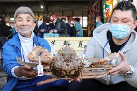 松葉ガニを１匹２５０万円で落札した男性（右）＝兵庫県新温泉町、浜坂漁港