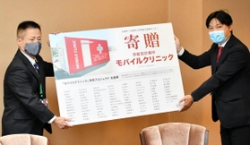 寄贈パネルを兵庫県の藪本訓弘健康福祉部長に手渡すヴィガラクスの横山和也社長（右）＝兵庫県庁