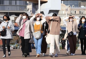 日差しを受けて軽装で歩く若者たち＝１９日午後、神戸市中央区波止場町