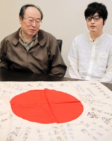 戦後７５年の節目に、姫路へ帰ってきた日章旗を見つめる岡本明さん（左）と四男崇宏さん＝姫路市本町