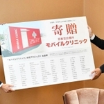 寄贈パネルを兵庫県の藪本訓弘健康福祉部長に手渡すヴィガラクスの横山和也社長（右）＝兵庫県庁