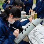 竹灯籠に筆で丁寧に文字を書き込む生徒たち＝神戸市北区山田町藍那