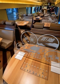 将棋盤などが刻印されたテーブルには新型コロナ対策のアクリル板が設置されている（撮影・秋山亮太）