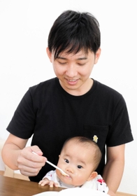 離乳食を与える男性。次女の成長を日々実感する＝神戸市垂水区