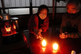 停電のため、ろうそくで明かりを確保する西村行雄さん夫妻＝１７日午後、兵庫県新温泉町歌長