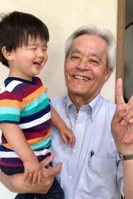 孫を抱く横野浩一さん（遺族提供）