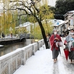 雪が降り積もった温泉街で朝湯巡りを楽しむ観光客＝１５日朝、豊岡市城崎町湯島
