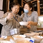 グループホーム「いなの家」で、職員と昼食の準備をする入居者（左）＝尼崎市食満（撮影・秋山亮太）