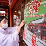 初詣の「分散参拝」やマスク着用を呼び掛けるポスターを張る巫女（みこ）＝神戸市中央区下山手通１、生田神社（撮影・秋山亮太）