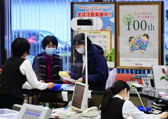 創立１００年のポスターを掲示し、新年初日の来店者を迎える尼崎信用金庫本店の窓口＝４日午前、尼崎市開明町３（撮影・中西幸大）