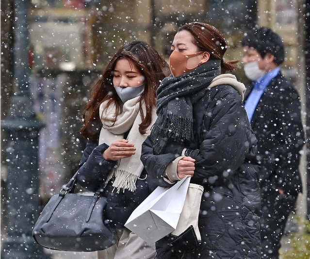 吹雪のように舞う雪の中を寒そうに歩く人たち＝８日午後、神戸市中央区三宮町３（撮影・秋山亮太）