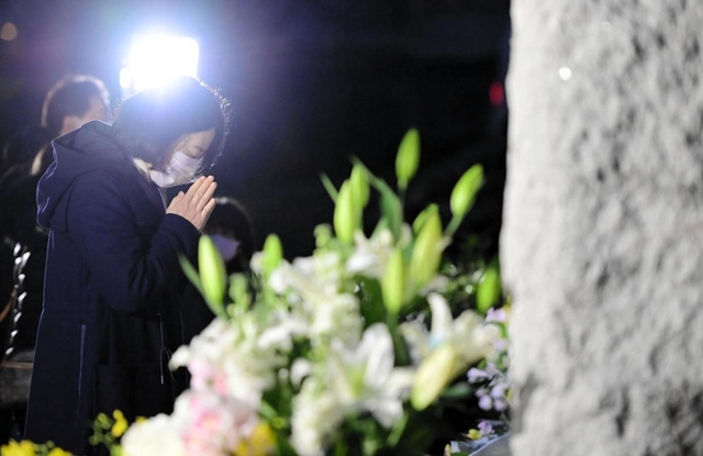 犠牲者の名前が刻まれた碑の前で手を合わせる人＝１７日午前６時４５分、西宮市奥畑、西宮震災記念碑公園（撮影・中西幸大）