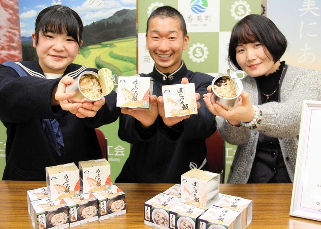 共同開発した炊き込みご飯の缶詰「のどぐろ飯」と「ほたるいか飯」をＰＲする（左から）香住高の北垣心望さん、西垣俊兵さんと但馬漁協職員＝兵庫県香美町香住区若松