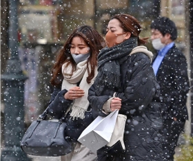 吹雪のように舞う雪の中を寒そうに歩く人たち＝８日午後、神戸市中央区三宮町３（撮影・秋山亮太）