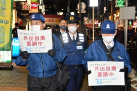 兵庫県の客引き行為等防止指導員に同行して外出自粛を訴える警察官（中央）＝神戸市中央区