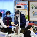 創立１００年のポスターを掲示し、新年初日の来店者を迎える尼崎信用金庫本店の窓口＝４日午前、尼崎市開明町３（撮影・中西幸大）