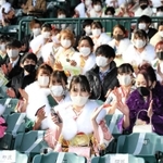 昨年に続き、甲子園球場が会場となった西宮市の成人式。１席ずつ空けて着席した新成人が三本締めをした＝１１日午後、西宮市甲子園町（撮影・後藤亮平）