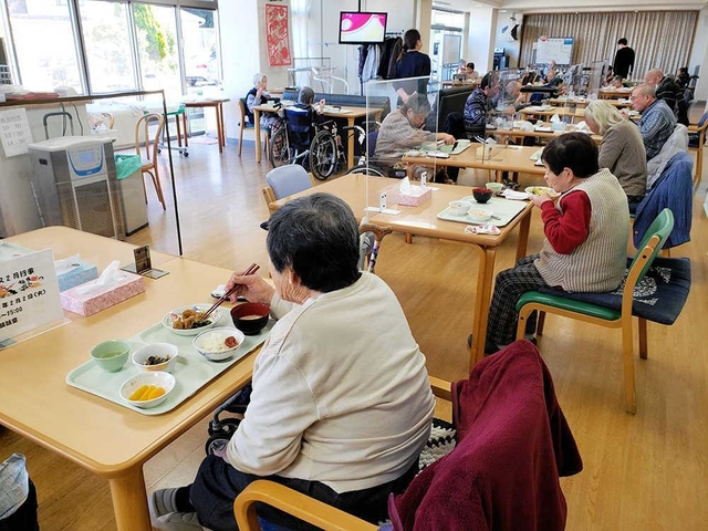 これまで感染者を出していない由良総合福祉センター。感染防止のため、デイサービスの利用者は仕切り板が置かれた机で食事をする＝洲本市由良