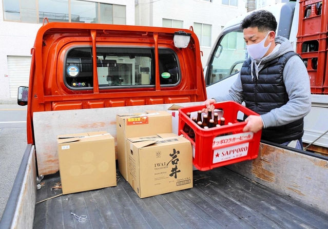 軽トラックの荷台にビール瓶を積み込むすずらん吉田商店の吉田寛さん＝神戸市北区鈴蘭台北町１