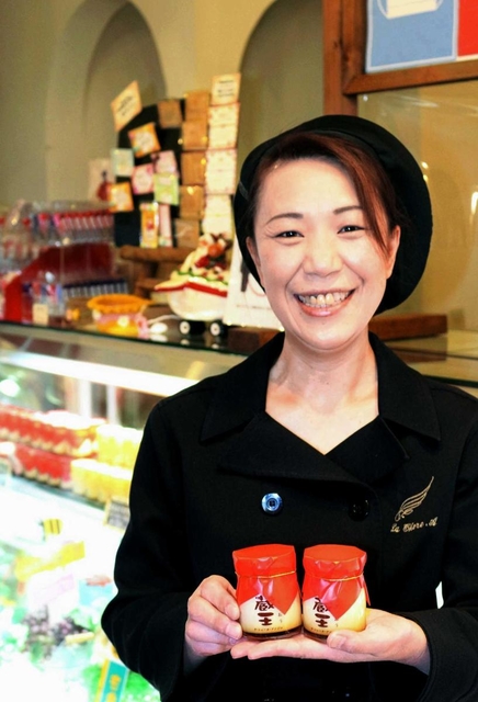 看板商品の「蔵王プリン」を手に持つ佐藤真由美さん。濃厚な味と、なめらかな口どけが特徴だ＝宮城県石巻市茜平