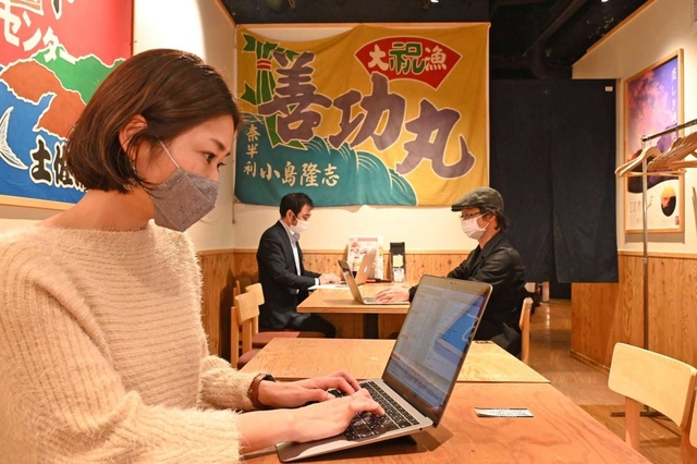 大漁旗が掲げられた店内でテレワークする利用客＝神戸市中央区北長狭通１