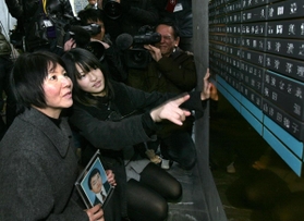 父の名前が刻まれた銘板を見つめる小島汀さん（左から２人目）＝２００９年１２月２０日、神戸市中央区加納町６