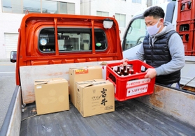 軽トラックの荷台にビール瓶を積み込むすずらん吉田商店の吉田寛さん＝神戸市北区鈴蘭台北町１