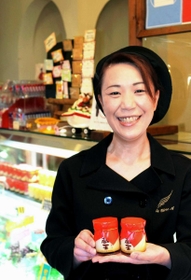 看板商品の「蔵王プリン」を手に持つ佐藤真由美さん。濃厚な味と、なめらかな口どけが特徴だ＝宮城県石巻市茜平