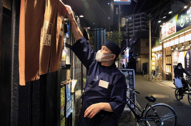 「客足が少ない」と、閉店時間を待たずにのれんを下ろすふぐ料理店主。一方で営業を続ける居酒屋もある＝１１日夜、伊丹市中央１（撮影・斎藤雅志）