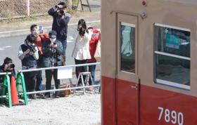 夢中で赤胴車にレンズを向ける鉄道ファンら＝４日午前、西宮市高須町２