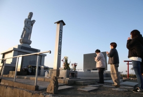 津波犠牲者を追悼する慰霊の塔を訪れ、手を合わせる人たち。すぐそばの波打ち際から潮騒がとどろく＝１１日午前６時２８分、仙台市若林区荒浜（撮影・小林良多）