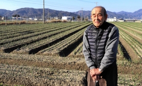 タマネギ畑の前に立つ谷口保さん＝南あわじ市中条中筋