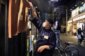 「客足が少ない」と、閉店時間を待たずにのれんを下ろすふぐ料理店主。一方で営業を続ける居酒屋もある＝１１日夜、伊丹市中央１（撮影・斎藤雅志）