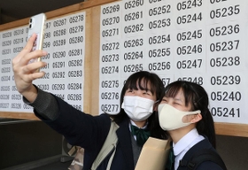 掲示板の前で記念撮影し、合格を喜ぶ受験生＝１９日午前、神戸市長田区寺池町１（撮影・長嶺麻子）