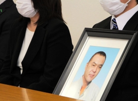 阪神・淡路大震災のがれき処理でアスベストによる中皮腫を発症し、死亡した明石市職員の男性の遺影を手に、勝訴判決後の会見に臨む遺族ら＝２６日午後２時４９分、神戸市中央区橘通３