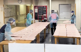 防護服を着て食事の配膳準備をする病院職員＝加古川市平岡町新在家、東加古川病院（同病院提供）