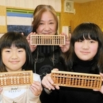 神山川の桜で作られたそろばんを手に持つ木村祐子さん（中央）とそろばん教室の児童ら＝宮城県気仙沼市本吉町窪