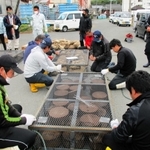 金属製の籠に肥料を入れる育波浦漁協青年部のメンバーら。手前は栄養塩を含む固形肥料、奥は農耕用が入った麻袋を搭載した＝２０２０年１１月、淡路市育波（同市提供）