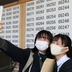 掲示板の前で記念撮影し、合格を喜ぶ受験生＝１９日午前、神戸市長田区寺池町１（撮影・長嶺麻子）