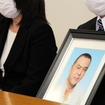 阪神・淡路大震災のがれき処理でアスベストによる中皮腫を発症し、死亡した明石市職員の男性の遺影を手に、勝訴判決後の会見に臨む遺族ら＝２６日午後２時４９分、神戸市中央区橘通３